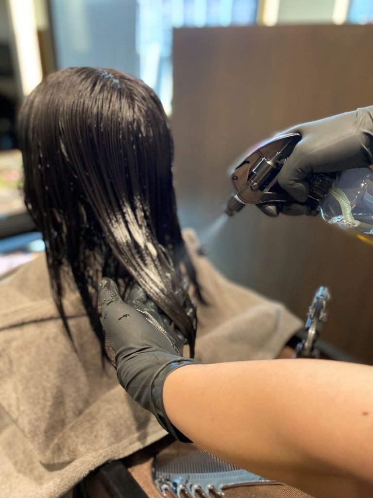 "徳島髪質改善MUNIONEのリペアメントエステでヘマチンを塗布し、残留アルカリを除去する施術風景"